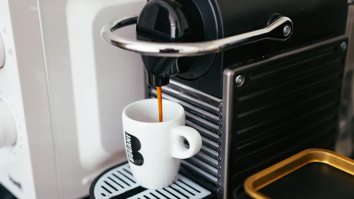 Une machine à capsules verse un café dans une tasse blanche